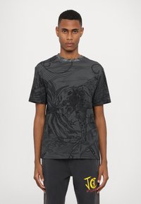 T-shirt graphique noir présentant un dessin linéaire détaillé d'un léopard et des motifs abstraits. Col rond, manches courtes, fabriqué en tissu doux.