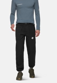 Zwarte outdoorbroek met een relaxte pasvorm, voorzien van riemlussen, meerdere zakken en een wit logo. Gemaakt van duurzaam, lichtgewicht materiaal.
