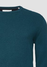 Türkiser Strickpullover mit Rundhalsausschnitt und gerippter Textur. Verfügt über ein kleines, auf der Brust eingesticktes Logo. Weicher Stoffeinsatz.