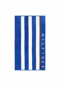 Blauwe handdoek met brede witte strepen, een accentband in rood en zwart, en de tekst "HILFIGER" in vette witte letters aan één kant.