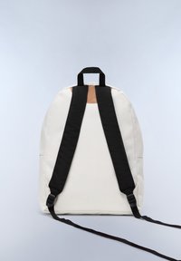 Zaino con un corpo in tessuto bianco crema, spallacci neri regolabili e un accento in pelle marrone sulla parte superiore, caratterizzato da un design semplice e arrotondato.