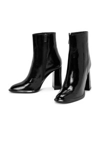 Bottines noires avec une finition laquée brillante, présentant un bout pointu et un talon carré haut, fermeture éclair sur le côté pour un enfilage facile.