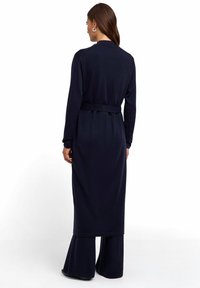 Granatowy długi kardigan z paskiem w talii, długimi rękawami i gładką teksturą; charakteryzuje się czystym, minimalistycznym wzornictwem bez ozdób.