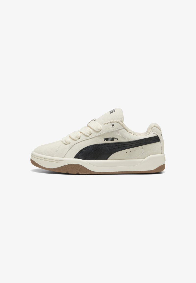 Lage crèmekleurige sneaker met zwarte Puma-streep, beige zool, vetersluiting en gevoerde kraag, getoond vanaf een zijaanzicht.