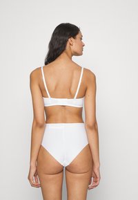 Hvit undertøysett med en enkel bralette med justerbare stropper og høyhåndt lage, begge med minimalistisk design og glatt tekstur.