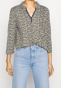 Blusa a maniche lunghe con sfondo blu navy e motivo floreale multicolore, colletto e tessuto leggero e testurizzato.