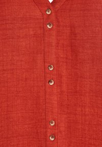 Camicia di lino rossa con scollatura a V, bottoni in legno sul davanti e un tessuto morbido e testurizzato con un sottile motivo mélange.