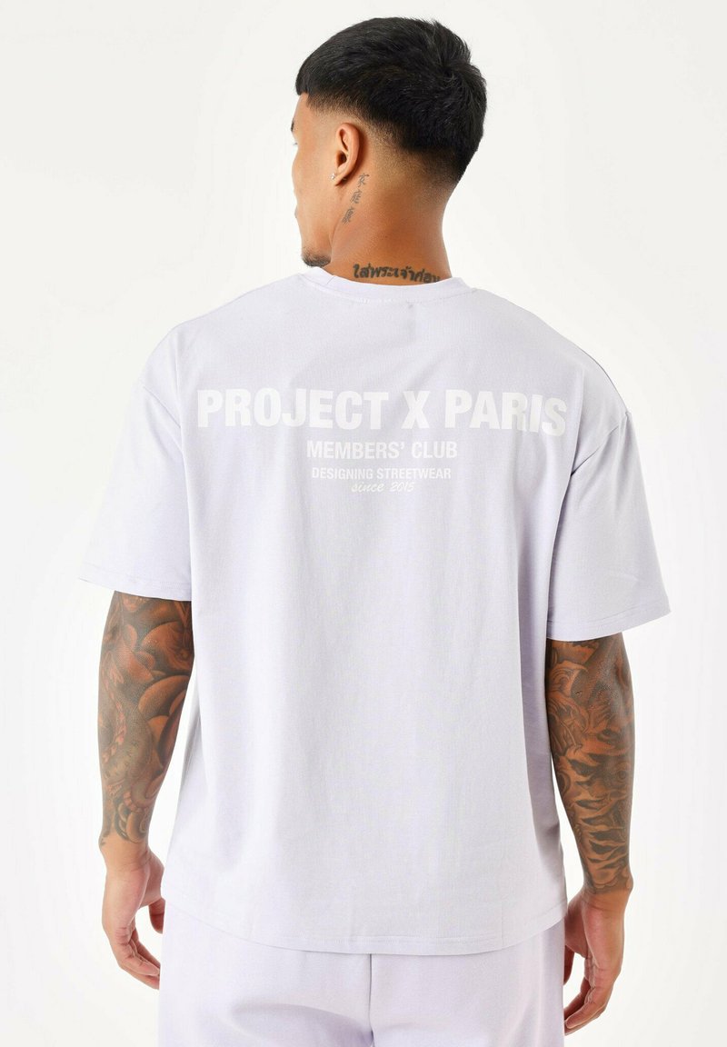Camiseta de algodón oversized de color púrpura claro con texto blanco en la parte posterior: "PROJECT X PARIS MEMBERS' CLUB DISEÑANDO STREETWEAR desde 2015."