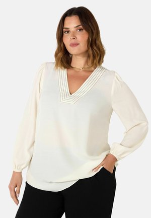 Halenka s výstřihem do V v barvě off-white, s dlouhými nafouklými rukávy, jemnými sklady u výstřihu a volným střihem.