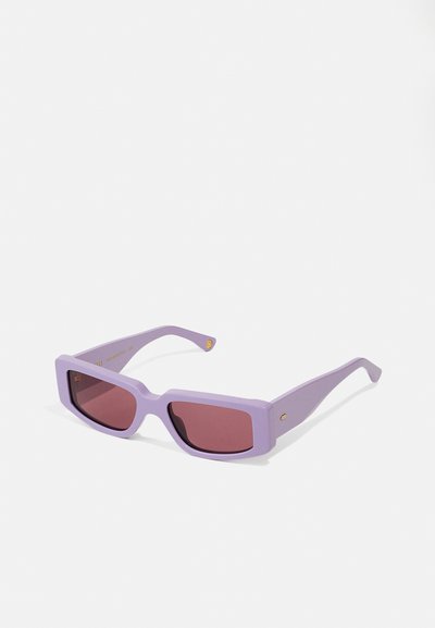 Lunettes de soleil carrées violettes avec des verres roses, présentant une finition mate et des accents dorés sur les branches. Conception légère.