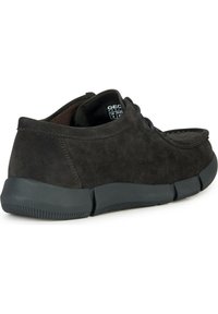 Chaussure en daim gris foncé avec un bout arrondi, un design à lacets et une semelle en caoutchouc noire dotée de rainures pour l'adhérence.