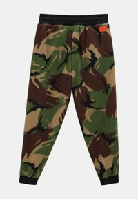 Jogging en polaire camouflage avec une taille élastique noire. Présente des motifs verts, bruns et beiges. Poignets aux chevilles.