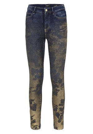 Jean skinny bleu foncé avec un motif floral doré délavé concentré sur le bas des jambes et un effet d’usure subtil sur le haut des cuisses.