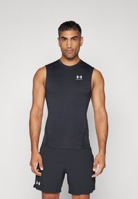 Svart ermeløs treningstopp og matchende shorts laget av elastisk stoff. Har rund hals og subtil logo på brystet.