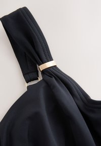 Cinturino in tessuto nero con dettaglio nodo annodato e accento in metallo dorato. Texture liscia e cuciture sottili sul cinturino.