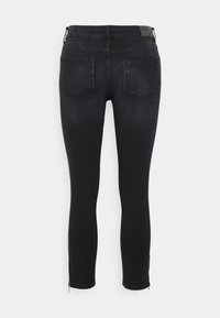 Jeans skinny pretos com uma textura suave, design de cinco bolsos e detalhes em zíper nos tornozelos. Vista traseira mostrando detalhes de costura.