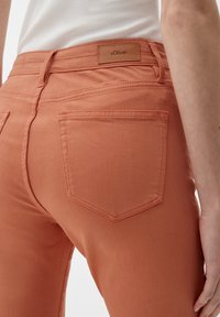 Pomarańczowe dżinsy o dopasowanym kroju, z dwoma tylnymi kieszeniami i skórzaną metką z marką "s.Oliver" blisko pasa.