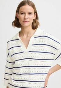 Letvægstrikpullover i creme med vandrette navy striber. Har V-hals og korte, løse ærmer. Tekstur med åbne stingdetaljer.