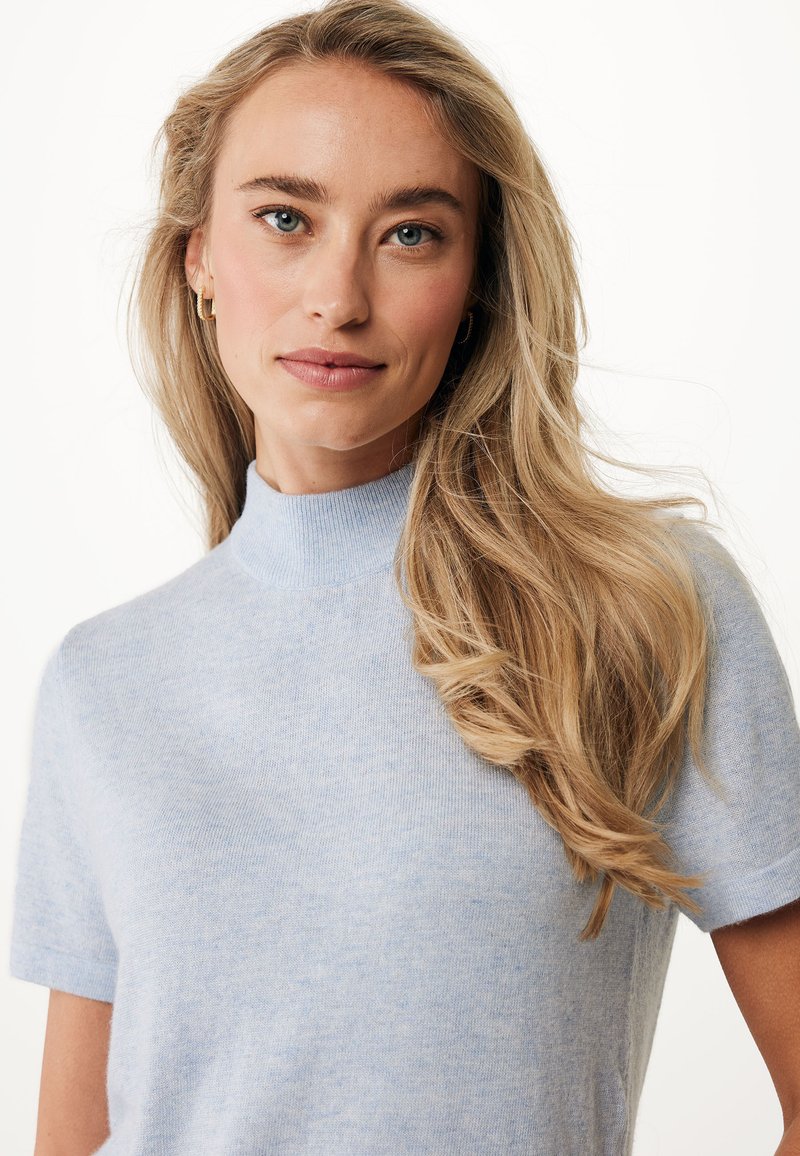 Jasnoniebieski sweter z krótkim rękawem i wysoką szyją, wykonany z miękkiej, teksturowanej tkaniny. Model charakteryzuje się luźnym krojem i subtelnym melanżowym wzorem.