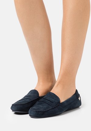 Navyblaue Wildleder-Pantoletten mit einer gesteppten Naht, einem glatten Obermaterial und einer flachen Sohle. Einfaches Design mit einem Akzentdetail an der Seite.