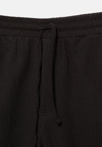 Czarne prążkowane joggery z elastycznym paskiem w talii ze sznurkiem, kieszeniami bocznymi i miękką fakturą.