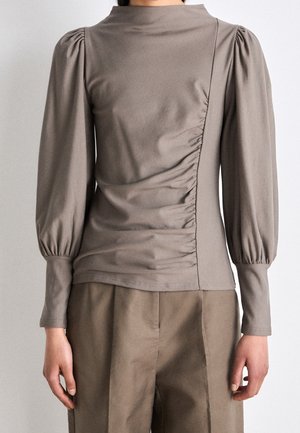 Taupe bluse med lange ærmer med rynket asymmetrisk frontpanel og puffede skuldre, parret med matchende taupe vidde bukser.