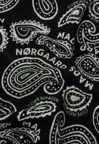 Svart stoff med hvite paisleymønstre og tekst. Designet inkluderer flere former med intrikate detaljer og kanter.