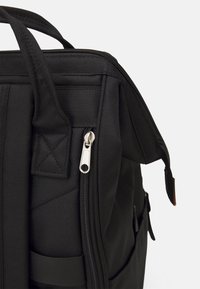 Czarny plecak z materiału o fakturowanej powierzchni, z metalowym zamkiem błyskawicznym, rączką u góry oraz boczną kieszonką na dodatkowe akcesoria.