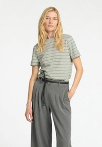 Gråstribet t-shirt med korte ærmer, kombineret med grå plisserede bukser med et sort snorebælte, hvilket viser et afslappet outfit.