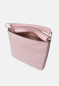 Ljusrosa läder axelväska med ett brett band, guldfärgad hårdvara och en delvis öppen dragkedja som avslöjar en brun innerfoder.