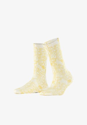 Chaussettes mi-mollet avec motifs floraux jaunes et lignes ondulées sur fond blanc, présentées côte à côte.