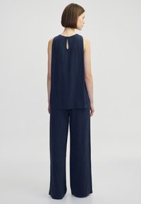 Námořnický dvoudílný outfit skládající se z bezramínek topu s detailním výřezem a kalhot s širokými nohavicemi. Materiál má texturovaný povrch.