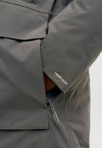 Hall gris tehniline jakk, millel on tõmblukuga tasku ja "TECHFUSION" logo varrukal. Sile tekstuur ja moodne lõige.