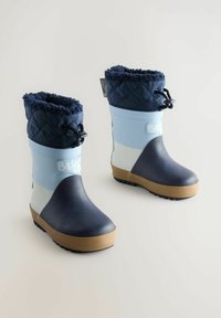 Botas de goma impermeables en azul marino y celeste. Cuentan con un puño de forro polar acolchado en azul marino con un cordón. Suela resistente en color beige con agarre texturizado.