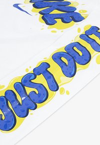 Weißer Stoff mit grafischem Text in Blau und Gelb, der die Phrase "JUST DO IT" in einem verspielten, plakativen Design darstellt.