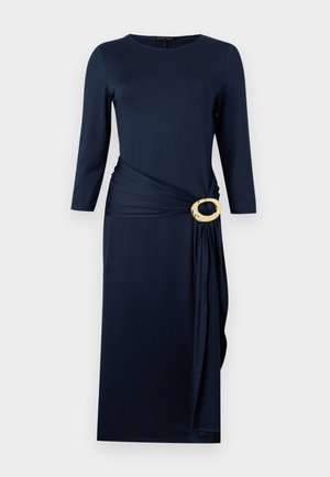 Φόρεμα μήκους έως το γόνατο σε ναυτικό μπλε χρώμα με μανίκια τριών τετάρτων, στρογγυλή λαιμόκοψη και ζώνη στη μέση με λεπτομέρεια διακοσμητικής χρυσής οβάλ αγκράφας.