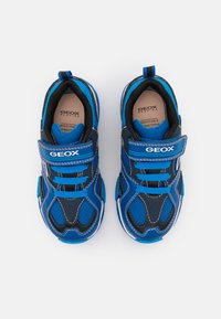 Blå og sorte sneakers lavet af åndbart stof, med velcrolukninger, mesh-detaljer og en hvid ydersål med kontraststing.