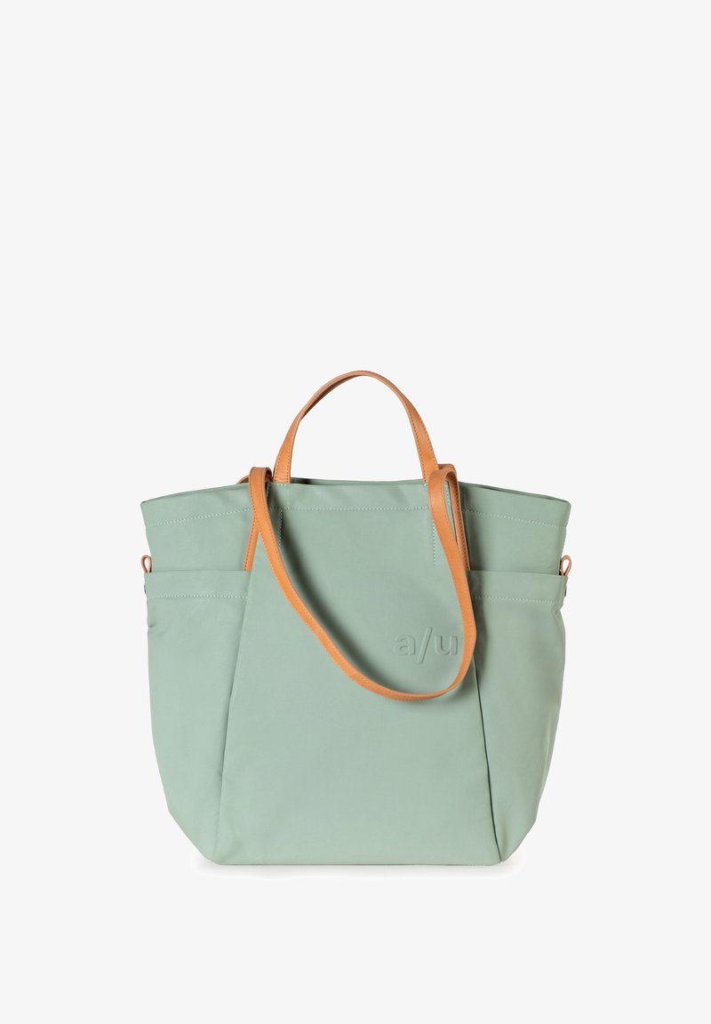Mintgroene totebag van zacht materiaal, met tanlederen handvatten, een zijzak en subtiele reliëflogo-detail.
