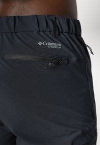 Crne Columbia Titanium kratke hlače s elastičnom trakom, vezicom i džepom na patentni zatvarač. Glatka tekstura i tkanina koja odbija vlagu.