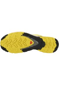 Suela de zapato de trail running con un diseño texturizado en amarillo y negro. Presenta patrones de agarre prominentes y acentos plateados en la media suela.