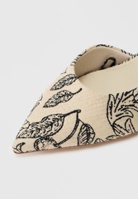 Μπλέιτς παπούτσι με μυτερή μύτη σε μπεζ ύφασμα με μαύρο μοτίβο φύλλου. Διαθέτει ανοιχτό σχέδιο και λεία εσωτερική επένδυση. Υφή εξωτερικής επιφάνειας.