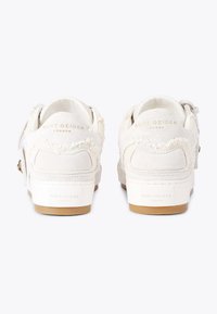 Sneakers bianchi in suede con dettagli in frange e suola in gomma. Il retro presenta un logo embossato e accenti dorati. Texture liscia in tutta la scarpa.