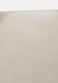 Lys grå veske laget av matt, vanntett materiale med en debossert "RAINS" logo i sentrum. Enkel, rektangulær design med jevn tekstur.