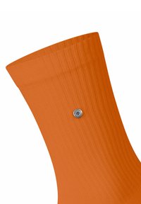 Orange gerippte Socke mit einem silbernen Knopfdetail in der Nähe des Knöchels, aus strukturiertem Stoff für zusätzlichen Halt und Komfort.