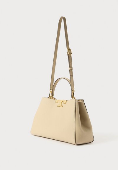 Beige leren handtas met een gestructureerde vorm, voorzien van een goudkleurig logoaccent en dubbele handvatten voor verschillende draagmogelijkheden. Inclusief verstelbare schouderriem.