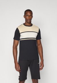 Camiseta de manga corta negra y beige con rayas horizontales, diseño de cuello redondo, material de algodón y detalle del logo en la parte superior izquierda del pecho.
