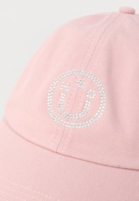 Șapcă de baseball roz deschis cu un design de față zâmbitoare împodobit cu rhinestones pe panoul din față.