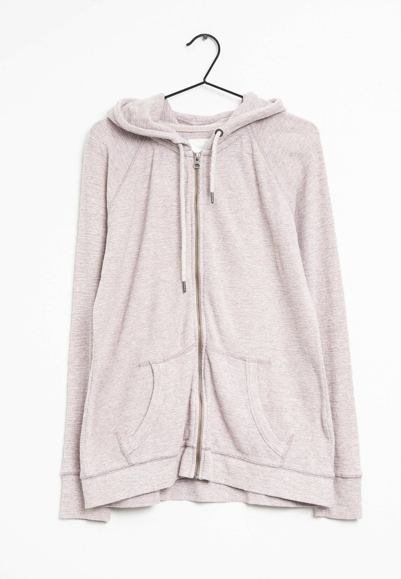 Hoodie zippé rose clair avec cordons et poches avant, suspendu à un cintre noir sur fond blanc.