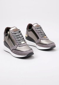 Zapatillas wedge en ante gris y material metálico, con cremallera frontal, puntera redonda y suela de goma blanca. Detalles dorados en el talón.