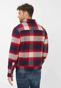 Red, white, and blue checkered flannel jacket with a collar and buttoned cuffs. Soft texture, semi-fitted design, and herringbone pattern accents.
